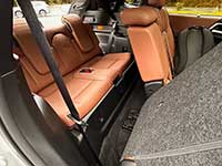 2026-Outlander-PHEV-seating - Portage La Prairie Voice Cargo area of a car with orange-brown leather rear seats folded down, gray carpeting, and a visible seat belt.